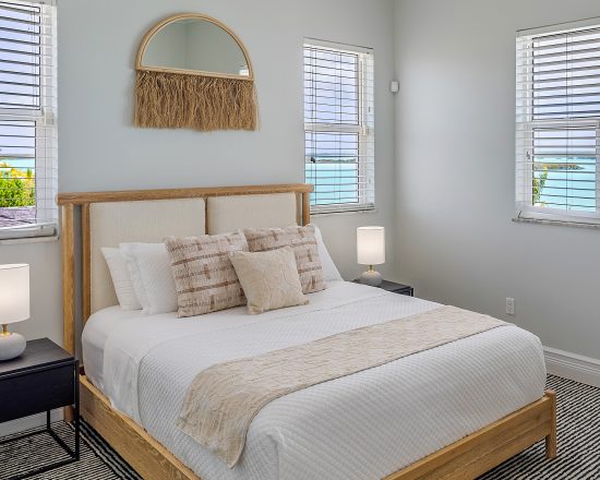 Blue Island Villa bedroom with wood framed bed and many windows