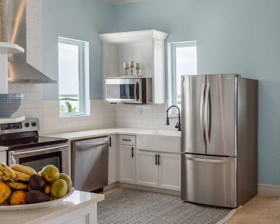 Blue Island Villa kitchen with blue walls, white modern cabinets, and stainless steel appliances