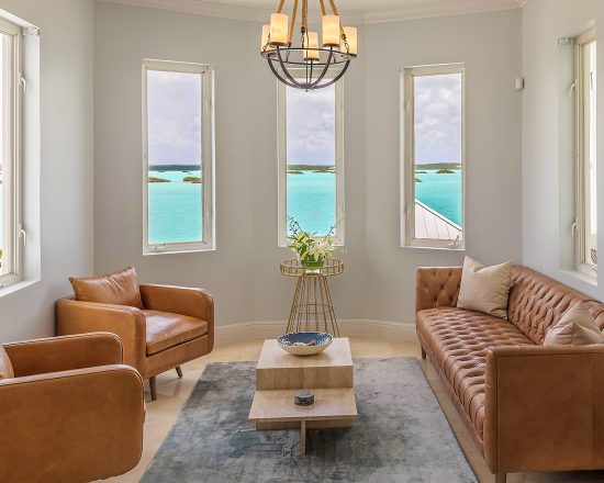 Blue Island Villa seating area with leather chesterfield, leather chairs, and water views