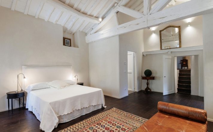 One of the bedrooms in Bella Aura with wooden floors, high ceilings, and a European king sized bed.