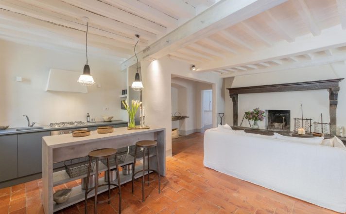 Bella Aura Kitchen and Living Area detail with wooden kitchen island, white sofa and walls, and tile flooring