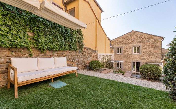 The outdoor couch in the seating area of the courtyard, with a cool leaf-covered stone wall behind