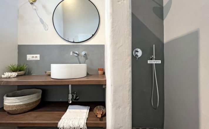 A bathroom at Bella Aura featuring a modern shower, vessel sink, and wooden shelves