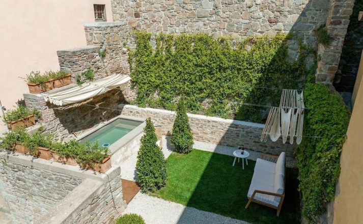 Private two-level Italian garden with an outdoor hydromassage jet tub, sun loungers, and stonework