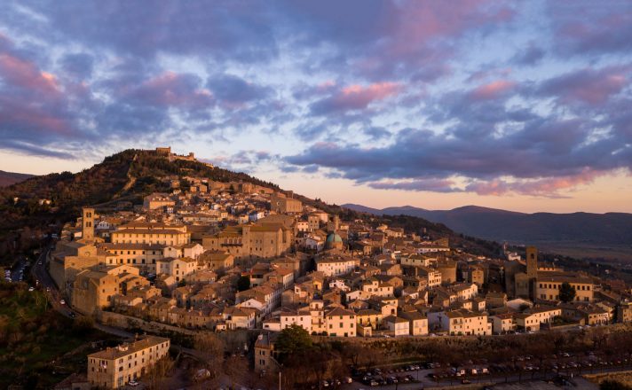 View of Cortona and its surrounding hillside, bathed in golden light