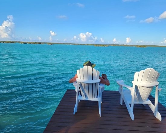 Blue Island Villa guest sitting on the end of the dock in a comfy Adirondack chair