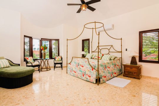 Spacious bedroom at Cabarete Dreams, showcasing the canopy bed with floral comforter and ceiling fan