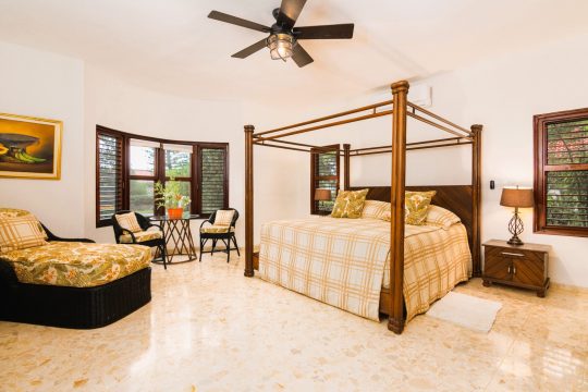 Spacious bedroom at Cabarete Dreams, showcasing the canopy bed with plaid comforter and ceiling fan
