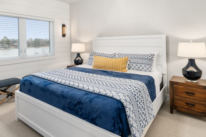 Beautiful and airy Bedroom 2, which features a white bed with Blue and white bedding, and white walls.